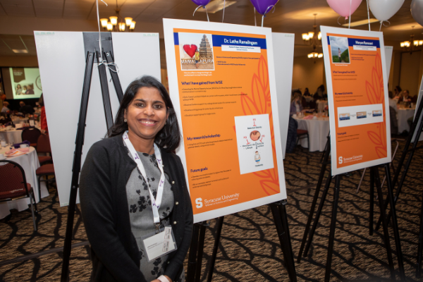 Dr. Latha Ramalingam smiling next to her poster